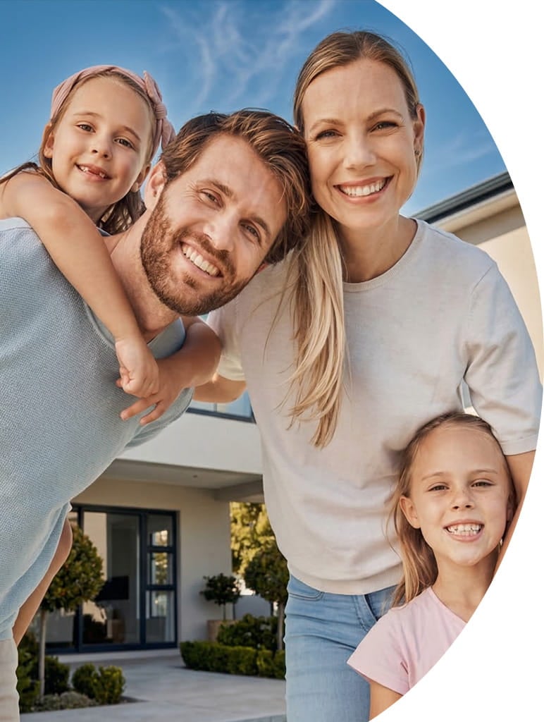 A happy family of four smiling outside their modern home. At our roofing company, our mission is to provide high-quality, durable roofs that protect families and give homeowners peace of mind.